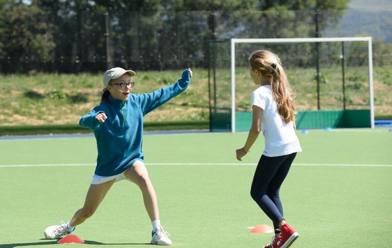 Zwei Mädchen wärmen sich während ihrer Schülersprachreise Schottland auf einem Fußballplatz auf