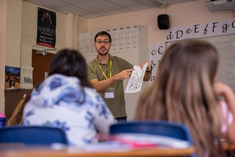 Ein Lehrer erklärt auf Sprachreise Schottland Schüler den Schüler etwas mit einem Blatt in der Hand 