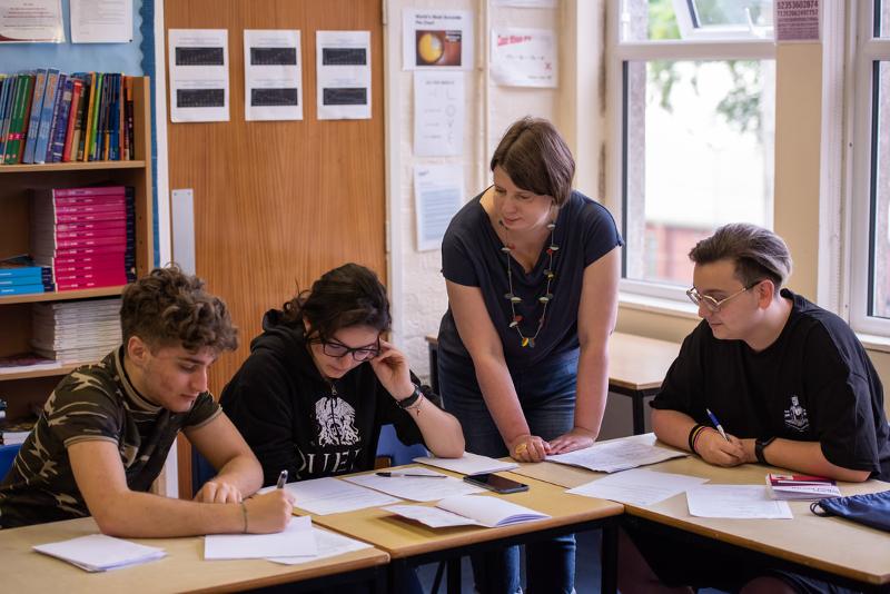 Eine Lehrerin hilft den Schüler auf Sprachreise nach Schottland bei den Aufgaben im Unterricht