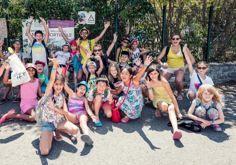 Eine Gruppe von Kindern hält auf Sprachreise Frankreich die Hände hoch