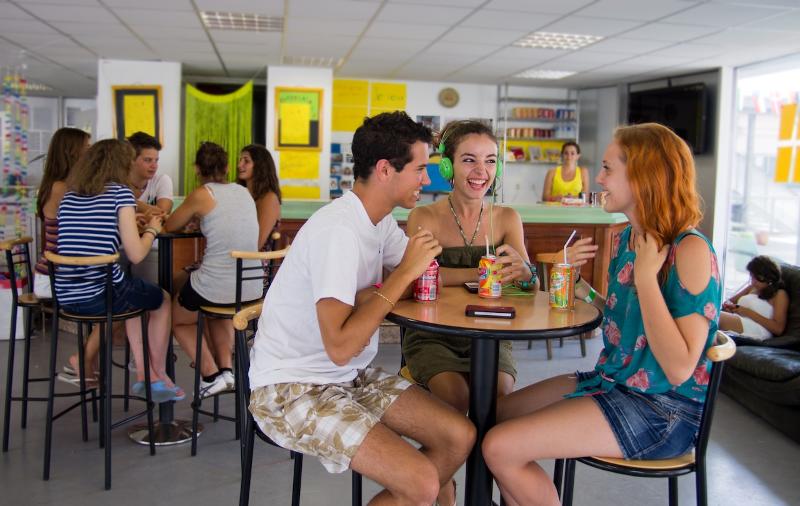 Teilnehmer der Frankreich Sprachreise lachen bei einem Drink gemeinsam