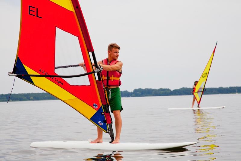 Teilnehmer der Sprachreise stehen auf Board und windsurfen
