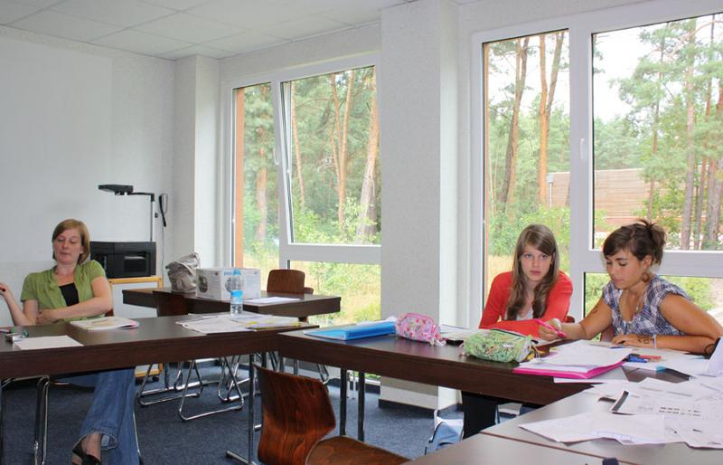 Auf Sprachreise gibt es große Klassenräume und drei Mädchen sitzen und lernen