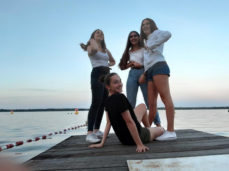 Vier Mädchen der Sprachreise stehen auf dem Steg am Wasser und lachen
