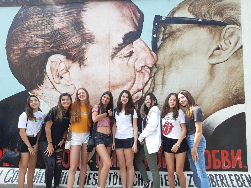 Auf Sprachreise macht eine Gruppe von Mädchen ein Bild vor einer Berliner Wand