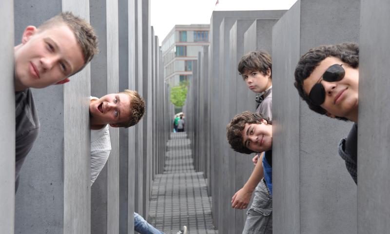 Die Teilnehmer der Sprachreise machen Bilder bei einem Denkmal und man sieht ihre Köpfe
