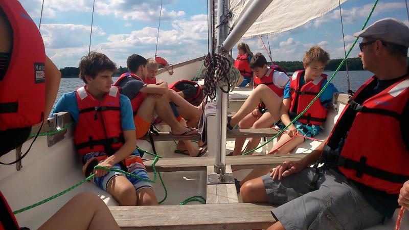 Die Kinder der Sprachreise sitzen auf einem Boot auf dem See mit Rettungswesten