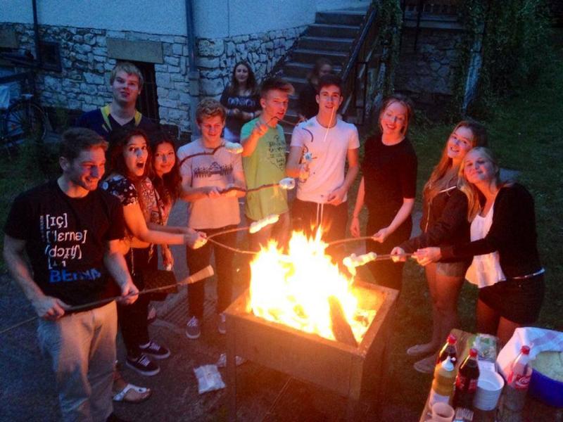 Die Teilnehmer der Sprachreise grillen Stockbrot über dem Lagerfeuer