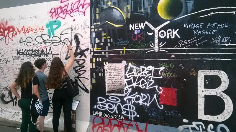 Drei Freunde auf Sprachreise schreiben an eine Wand