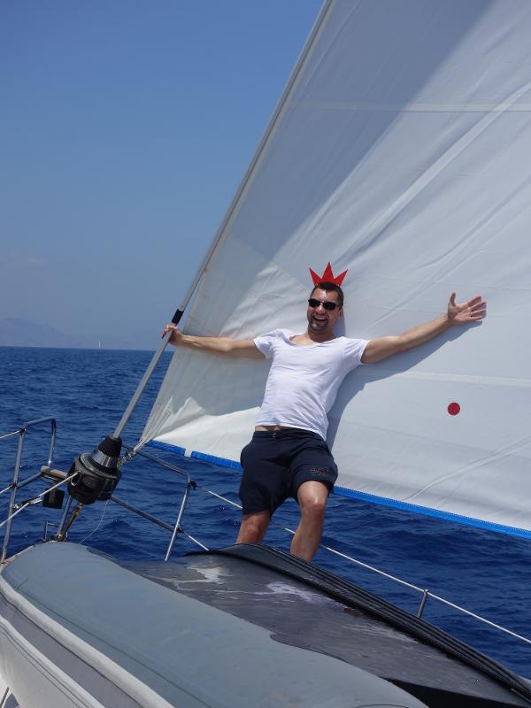 Ein Mann steht bei einer Jugendreise ab 18 auf einem Boot vor einem Segel