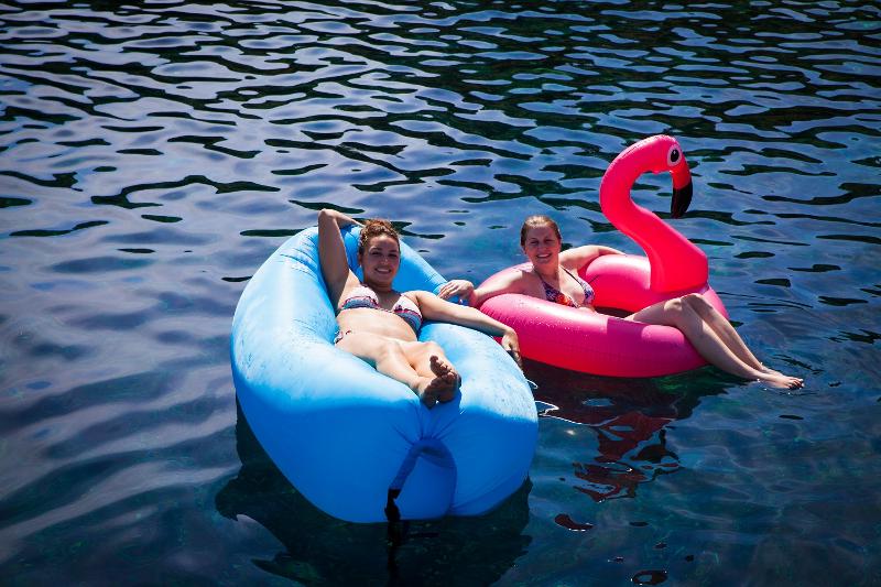 Zwei Teilnehmerinnen entspannen bei einer Jugendreise ab 18 auf zwei Schwimm-Flamingos