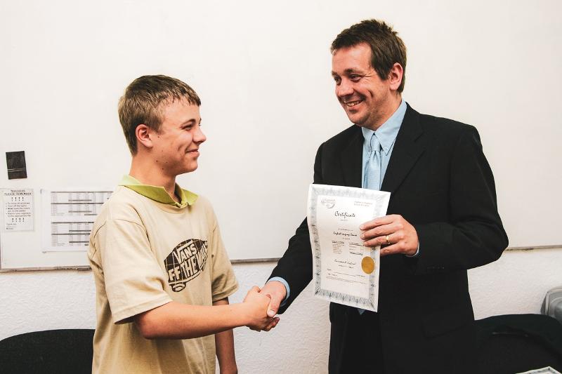 Einem Schüler wird am Ende seiner Sprachreise Englisch England ein Zertifikat überreicht