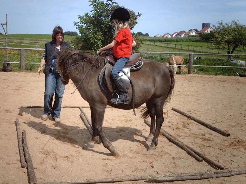 Im Ferienlager ab 7 sitz ein Mädchen auf einem Pferd und übt das Reiten