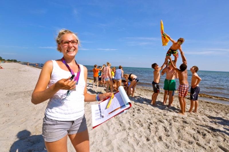 Betreuerin post vor Gruppe am Strand im Ostsee Jugendurlaub