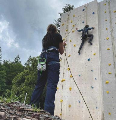 Ein Junge klettert im Outdoor Ferienlager an einer Kletterwand
