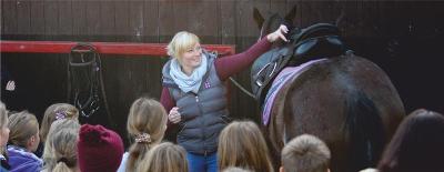 Eine Reitlehrerin zeigt in Ferien Ponyhof den Teilenehmern etwas