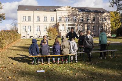 Kinder sitzen draußen an Tischen im Englischcamp in Brandenburg