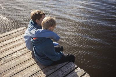 Jungs sitzen am Steg im Englischcamp in Brandenburg