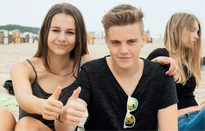 Mädchen und Junge zeigen Daumen hoch im Ferienlager an der Ostsee
