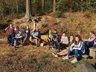 Kindergruppe sitzt am Waldrand auf der Ferienfreizeit in Belgien
