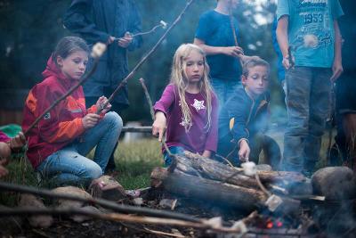 Kinder beim gemeinsamen Lagerfeuer und Stockbrot im Native Abenteuercamp