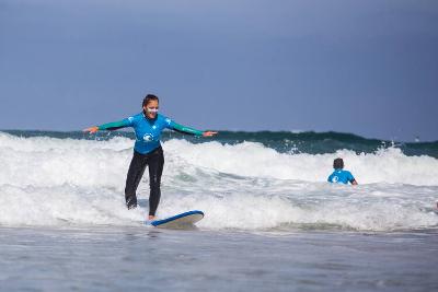 Junge Frau reitet auf Welle im Surfcamp in Frankreich