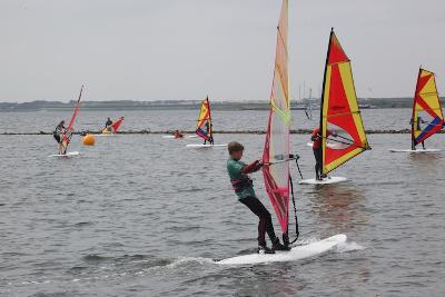 Teilnehmer eines Windsurfcamps haben Segelkurse