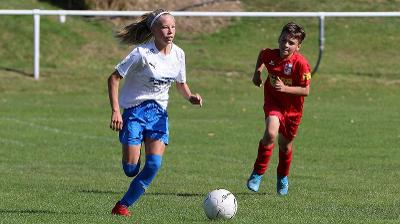 Ein Mädchen einer Fußball-Schule Ferien dribbelt einen Ball