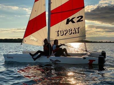 Eine Gruppe eines Feriencamps am Wasser segelt