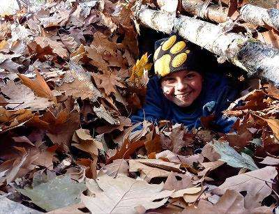 Ein Junge eines Zeltcamps versteckt sich im Laub