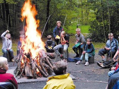 Teilnehmer einer Ferienfreizeit Hannover sitzen gemeinsam um ein Lagerfeuer