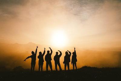 Teilnehmer eines Ferienlager in der Schweiz stehen im Sonnenaufgang