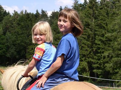 In den Ferien auf dem Ponyhof gehen Kinder reiten