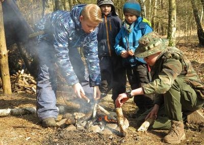 Ein Junge hält Pfeil und Bogen im Survival Camp in der Hand