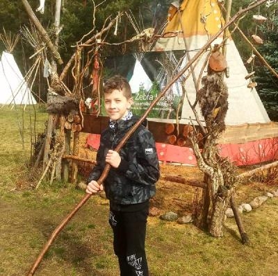 Ein Junge vom Survivalcamp hält einen langen Stock in der Hand