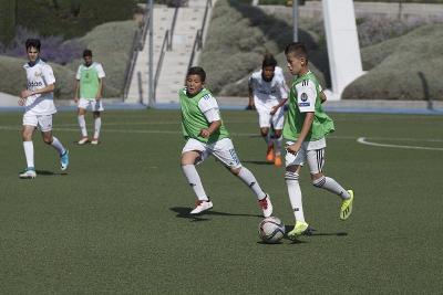 Ein Junge dribbelt im Fußballcamp mit dem Ball am Fuß über den Platz
