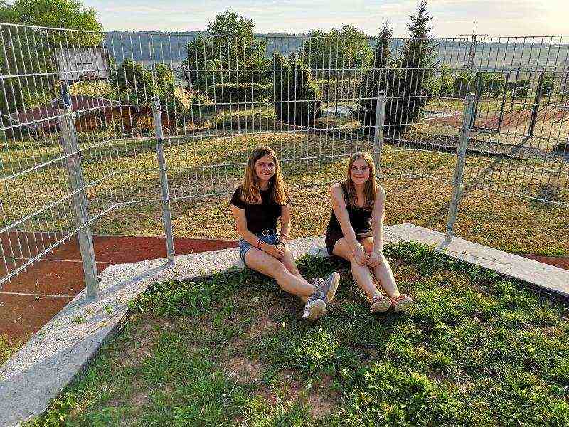 Zwei Mädchen sitzen auf der Wiese im Ferienlager für 16 Jährige