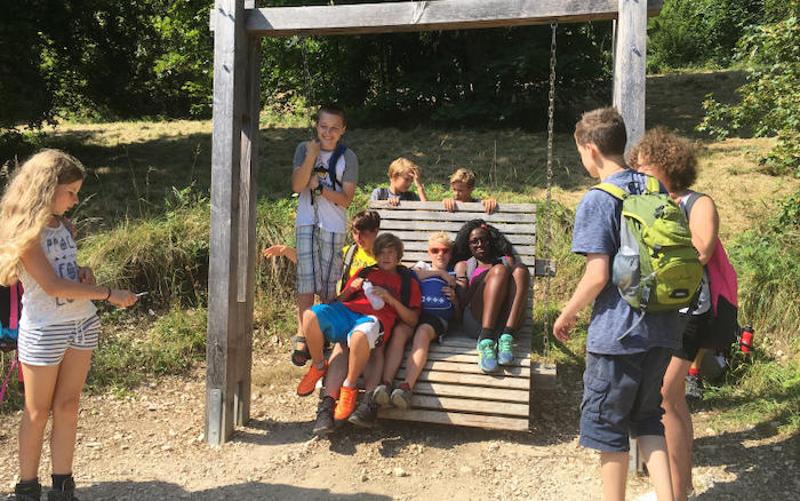 Kinder sitzen gemeinsam auf einer Bank in den Ferienfreizeiten Offenbach