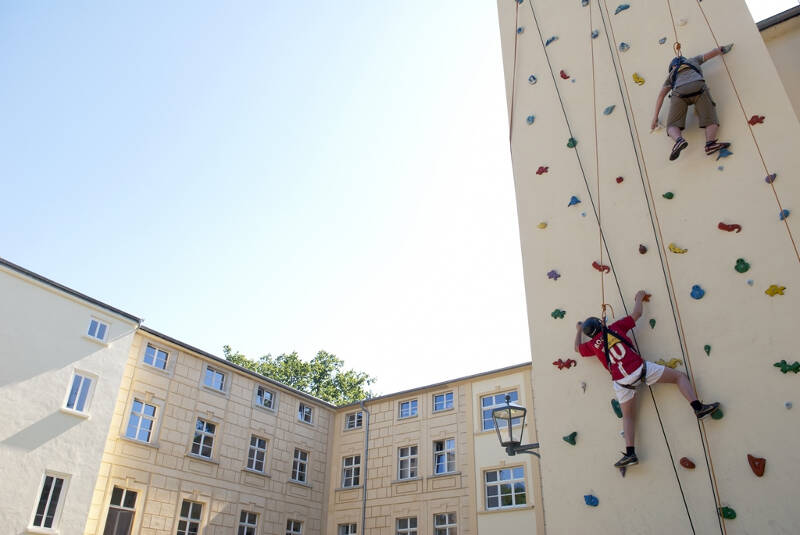 Die beige Kletterwand an der Außenseite von Schloss Gadow mit 2 kletternden Jungen