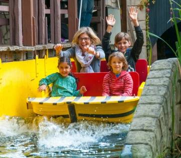 Familie lacht im Boot bei der Wildwasserfahrt im Filmpark Babelsberg