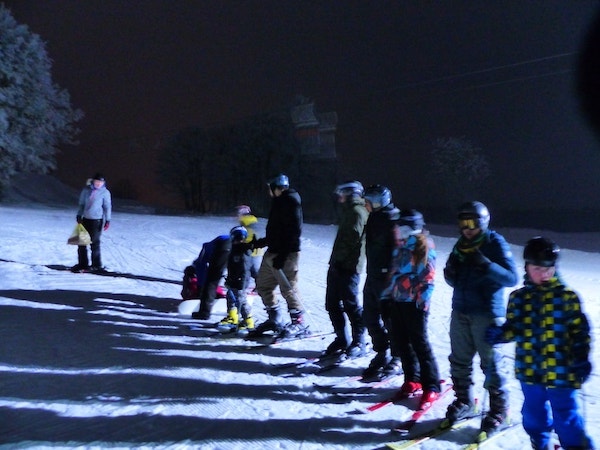 Gruppe Kinder bei Nacht bei Aktivitäten im Winter