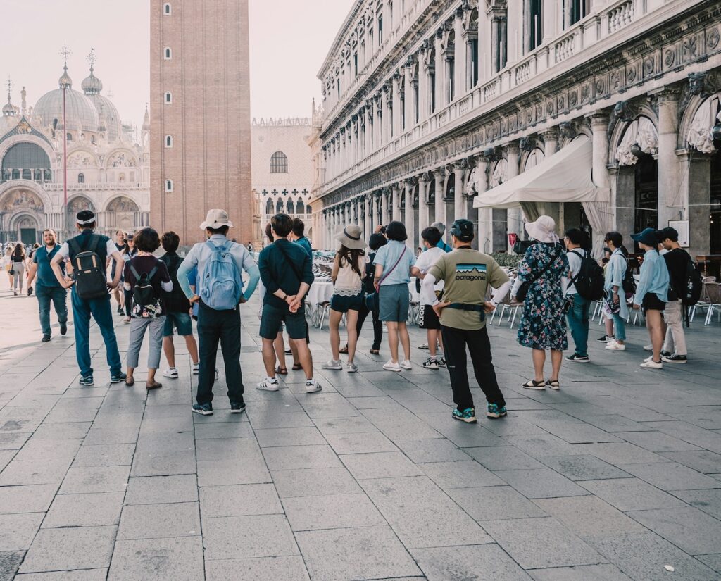 Stadtführung: Eine Gruppe von Touristen folgt einem Guide durch malerische Straßen, während dieser interessante Informationen zur Geschichte und Kultur der Stadt gibt.